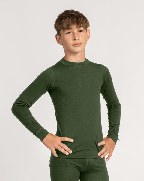 A child stands against a white background with their hands resting on their hips, wearing a fitted, dark green long-sleeve top and matching leggings. They are looking directly at the camera with a neutral expression.
