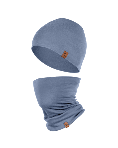 A product shot featuring a matching set of a dusty blue beanie hat and a tubular neck gaiter floating against a pure white background. The hat is positioned slightly above the gaiter, showing the natural drape of the fabric. Both items feature a small, square brown leather logo patch.