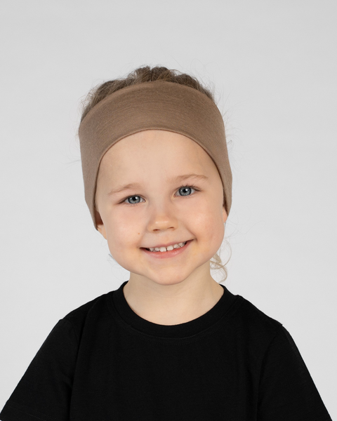 A close-up studio portrait of a smiling young child looking directly at the camera against a plain light grey background. She is wearing a black short-sleeved t-shirt and a wide, light brown headband.