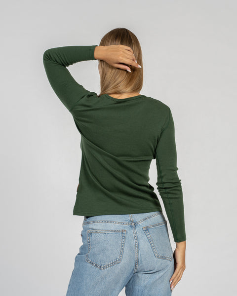 The menique women's merino wool dark green long sleeve top matched with classic light blue jeans, back view.