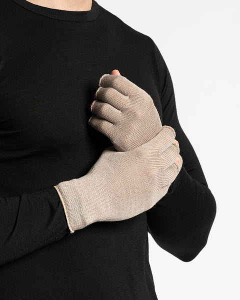 A person wearing a black long-sleeved shirt is shown from the chest up, putting on creamy beige fingerless gloves. The background is white.