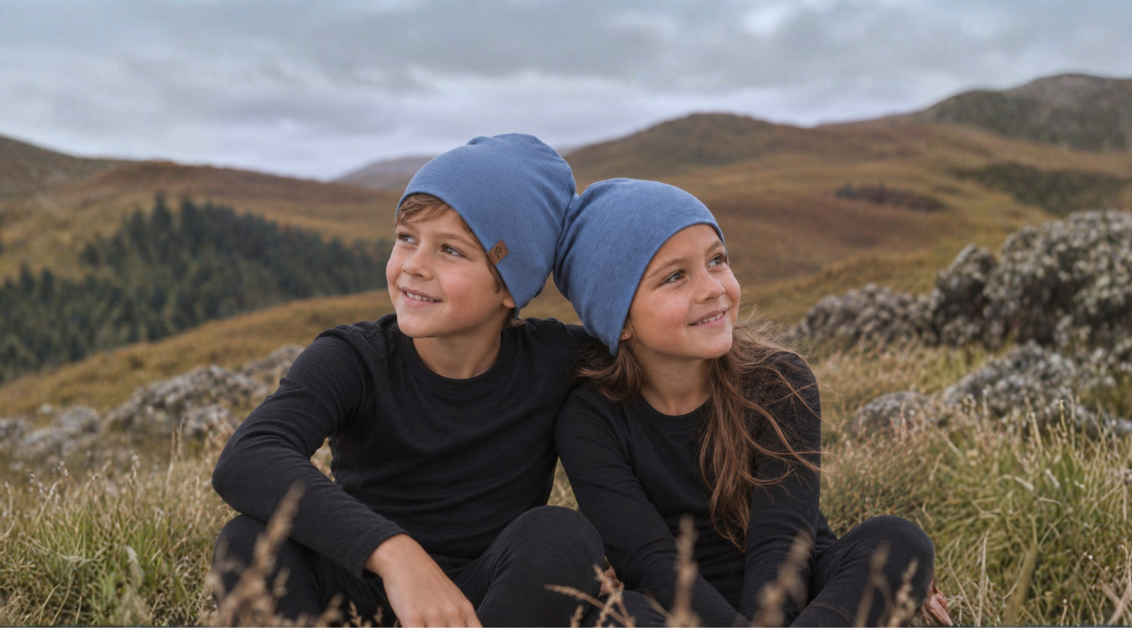 A baby girl wearing a royal cherry long sleeve merino wool shirt and a perfect gray merino wool knit beanie, pointing her finger at something.