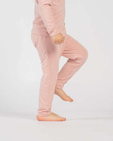 Child wearing pink bamboo long-sleeve top and matching pants, standing barefoot against a plain light background.