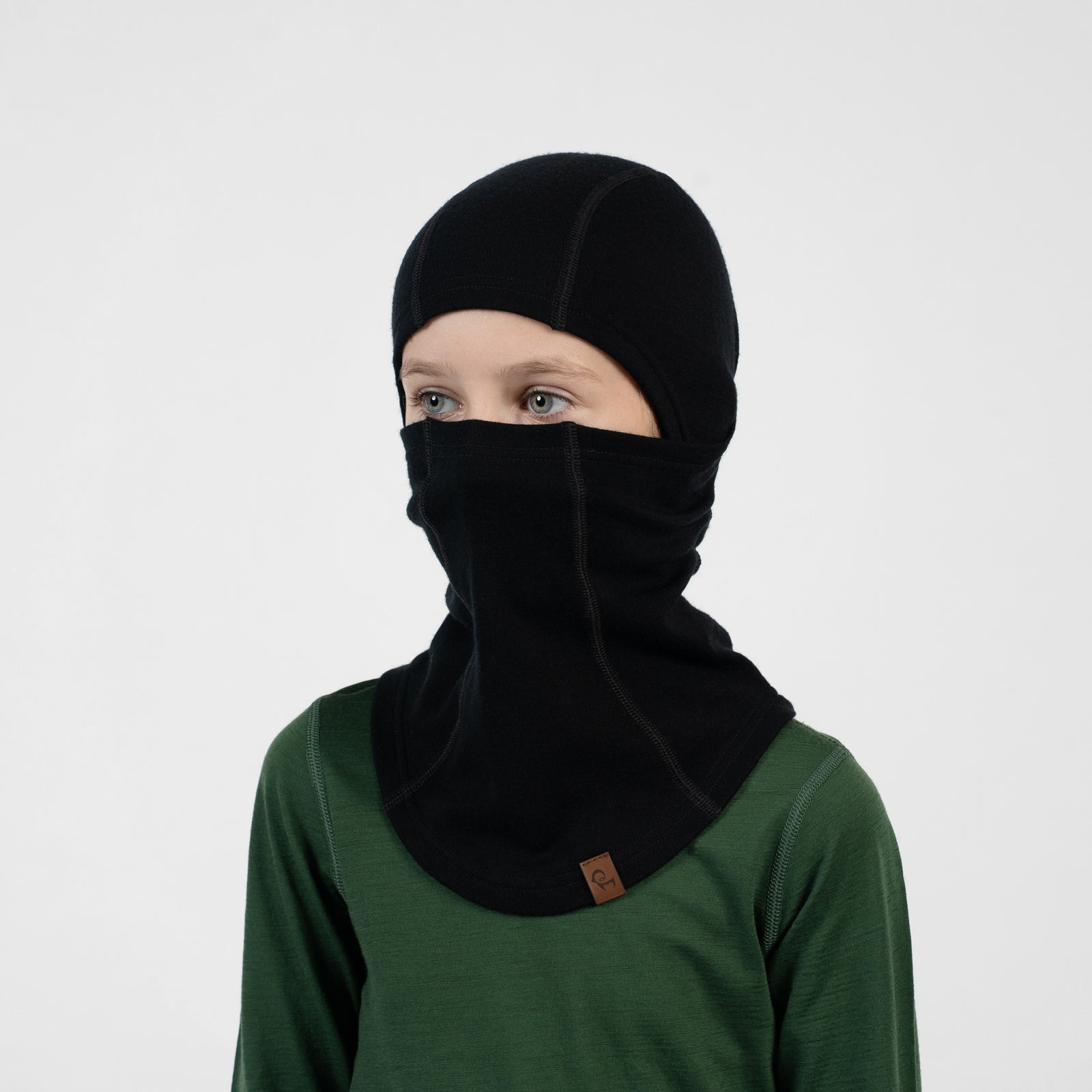 Child in a blue long-sleeve shirt wearing a black balaclava covering their head and pulled up over their nose and mouth.