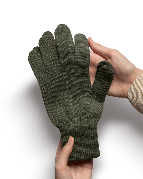 Dark gray Merino wool knit glove held in hands to display softness, stitching, and ribbed cuff.