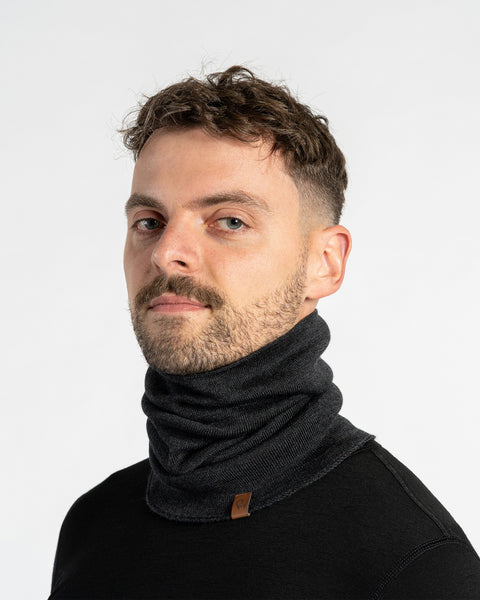 Man wearing a dark gray merino wool gaiter with a black shirt on a white background