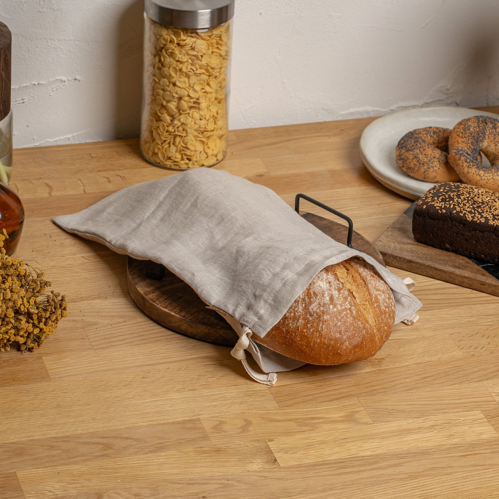 Bread in a reusable fabric bag on a wooden board with a wooden surface background