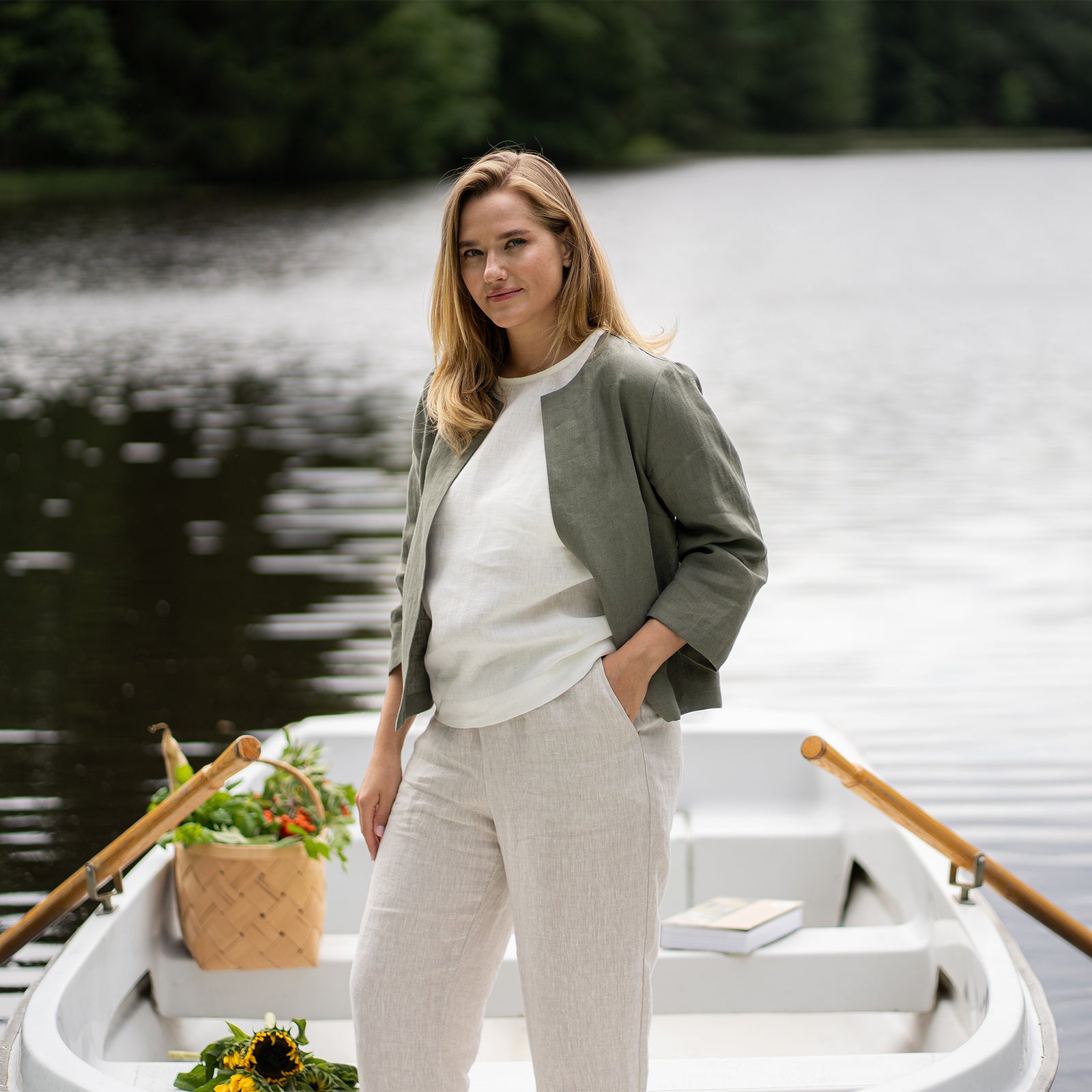 Woman wearing a natural linen jacket and pants with a blue top against a plain background