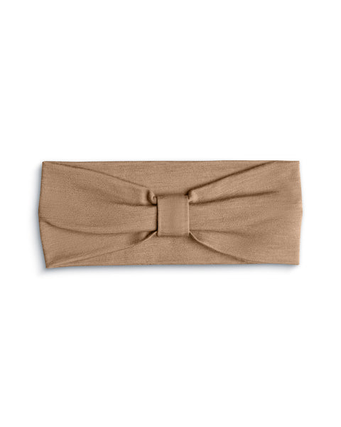 A product shot of a beige fabric headband laid flat against a plain white background. The headband features a gathered center detail with a matching fabric wrap, creating a subtle bow or ribbon effect.