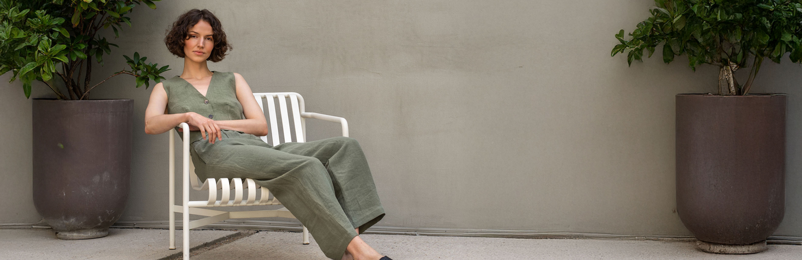 Woman in green linen outfit sitting on chair outdoors