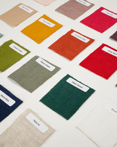 A flat-lay grid of various fabric swatches in colors like mustard, olive, burgundy, and navy, each with a small white identification label.