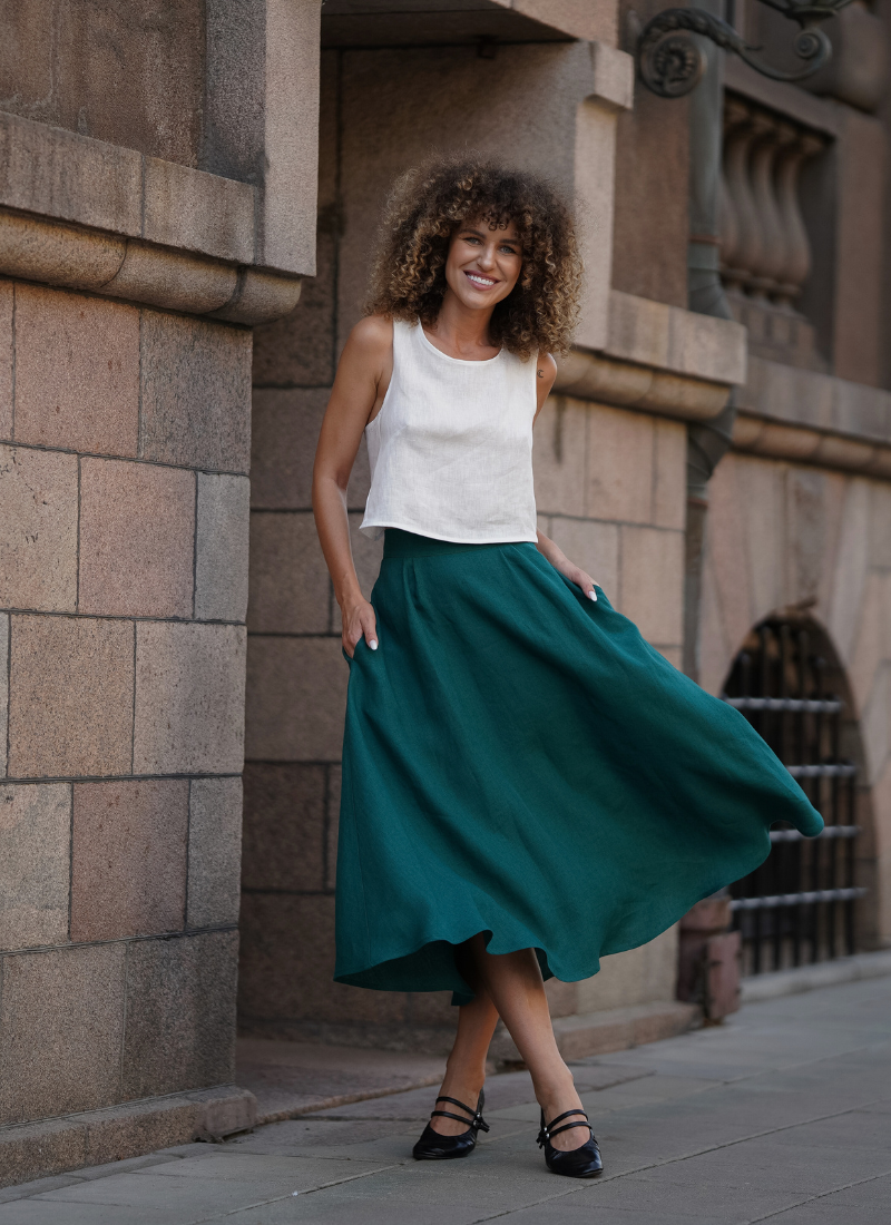 Woman in white top and green skirt walking along city street
