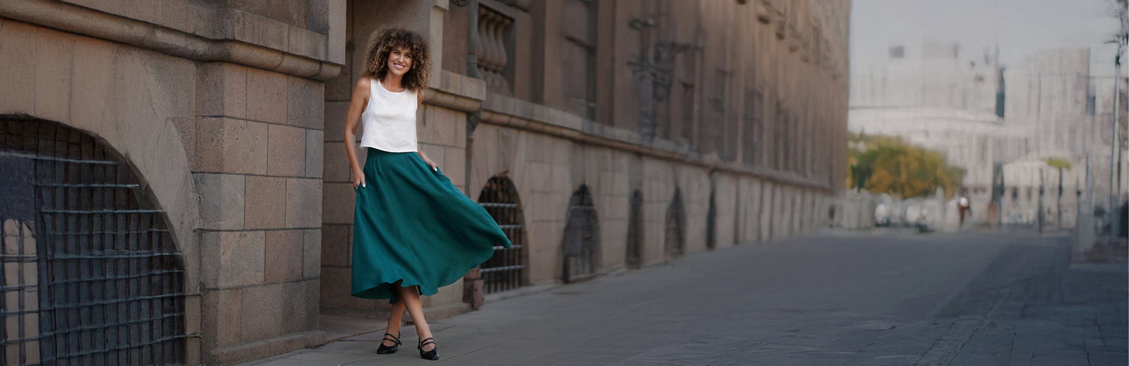 Woman in white top and green skirt walking along city street