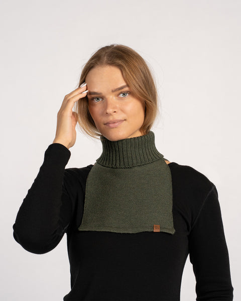 Woman wearing a dark green knitted merino wool dickie neck warmer over a black top, front view.