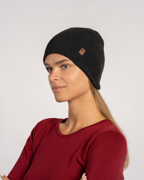 Side view of woman in a dark gray knitted Merino wool beanie, paired with a red shirt.