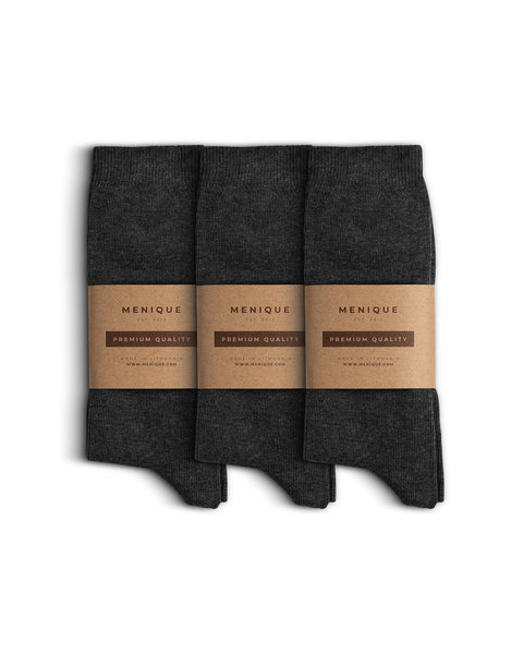 Set of three pairs of cotton socks, neatly folded and wrapped with Menique’s minimalist brown kraft paper packaging labeled ‘Premium Quality.