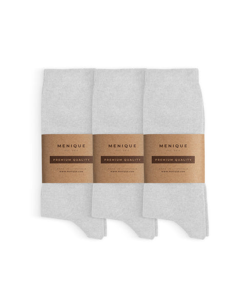 Set of three pairs of cotton socks, neatly folded and wrapped with Menique’s minimalist brown kraft paper packaging labeled ‘Premium Quality.