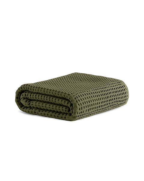 A neatly folded, olive green waffle-weave towel isolated on a pure white background. The deep waffle texture is clearly visible.