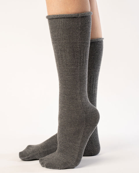A woman wearing long merino wool socks in dark gray color.