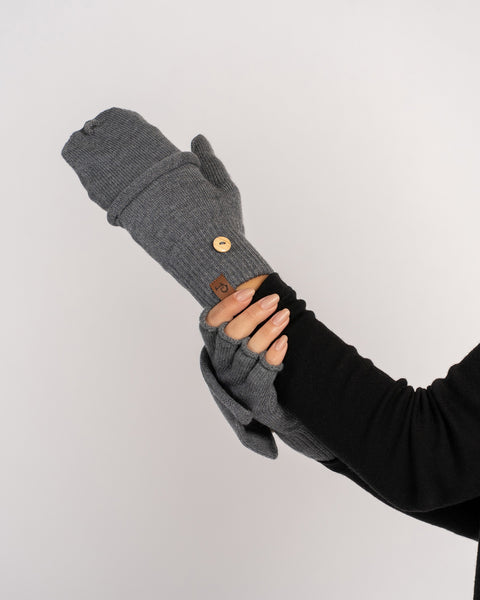 Model holding a gray convertible mitten in one hand while the other hand wears the matching fingerless glove, wooden button visible.