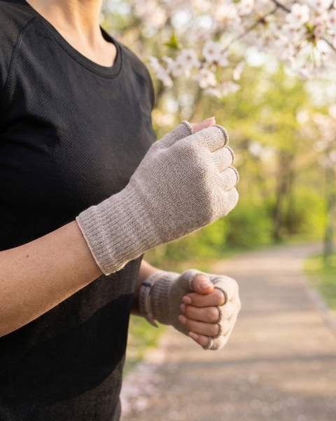 Woman running in spring park wearing beige merino wool fingerless running gloves, lightweight breathable gloves for temperature regulation and outdoor workouts