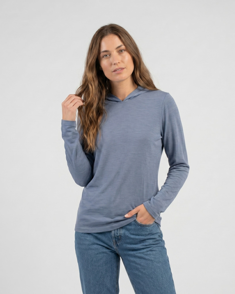 Dusty blue women’s hoodie is shown styled with jeans, featuring a smooth pullover hood and easy everyday drape.